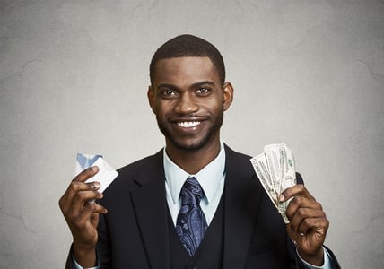 Closeup portrait happy, smiling business man company employee standing, holding dollar bills, credit card hand isolated grey black background. Banking exchange rate concept. Facial expression reaction