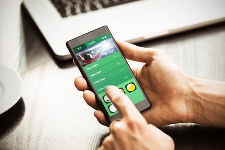 Hand holding smartphone against gambling app screen