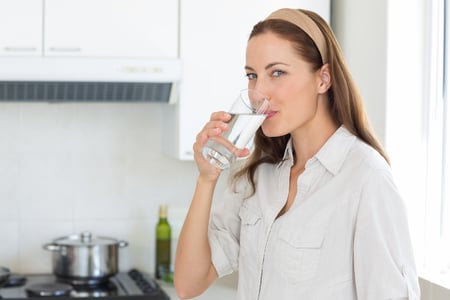 Portrait of a young woman drinking water in the kitchen at home
