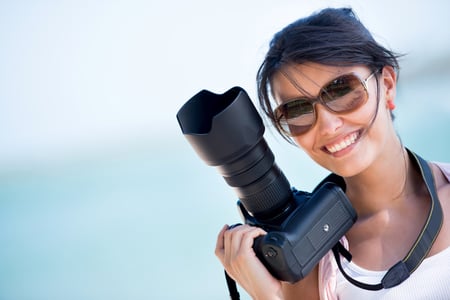 Professional female photographer holding a camera and smiling
