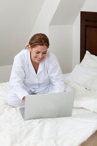 Woman sitting on her bed with a laptop